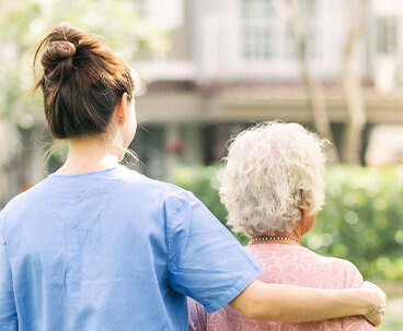 Nurse Caregiver Walking With Elderly Woman